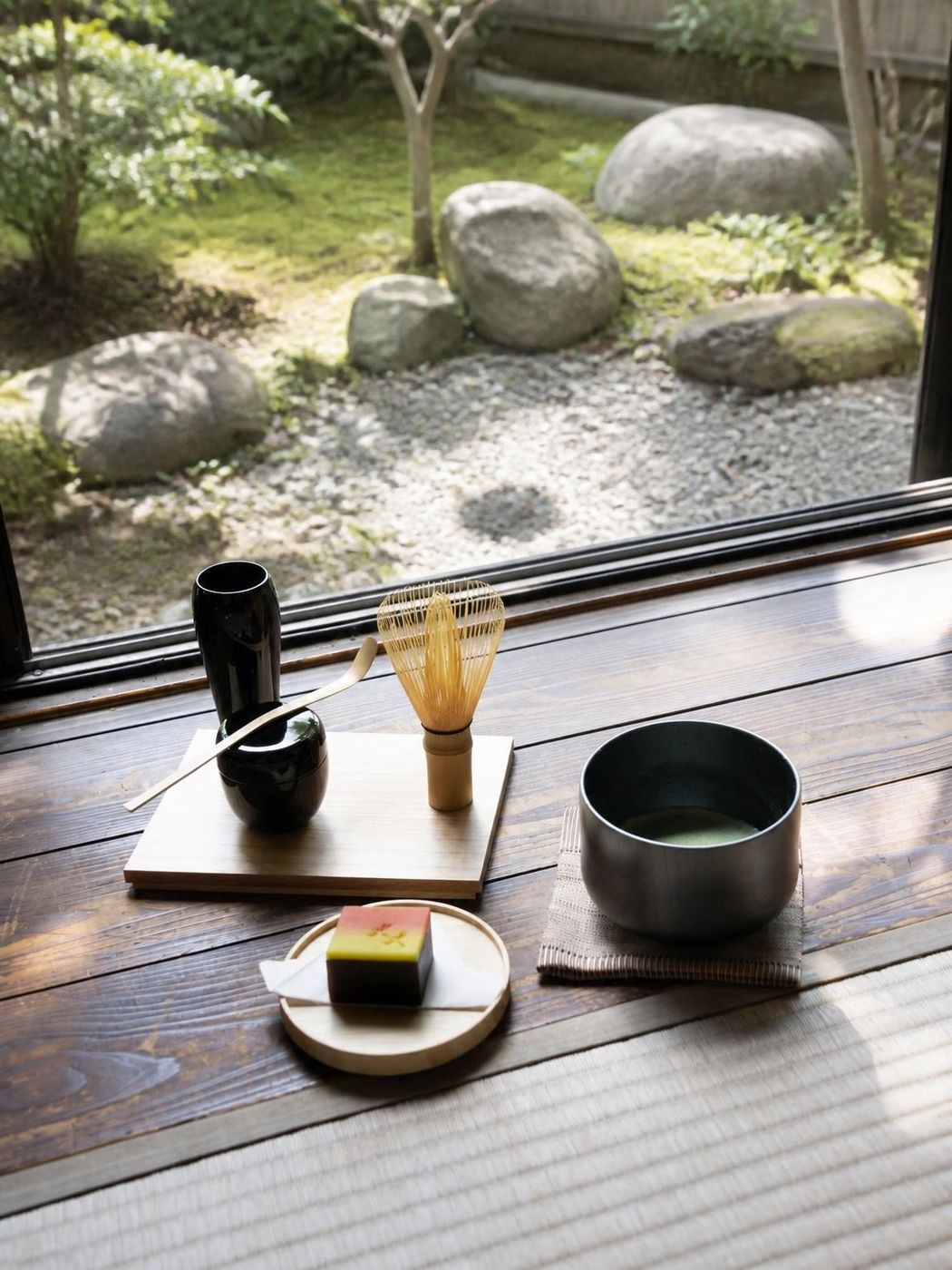 Traditional Japanese matcha tea ceremony flat lay with bamboo whisk and chawan bowl near a stone garden